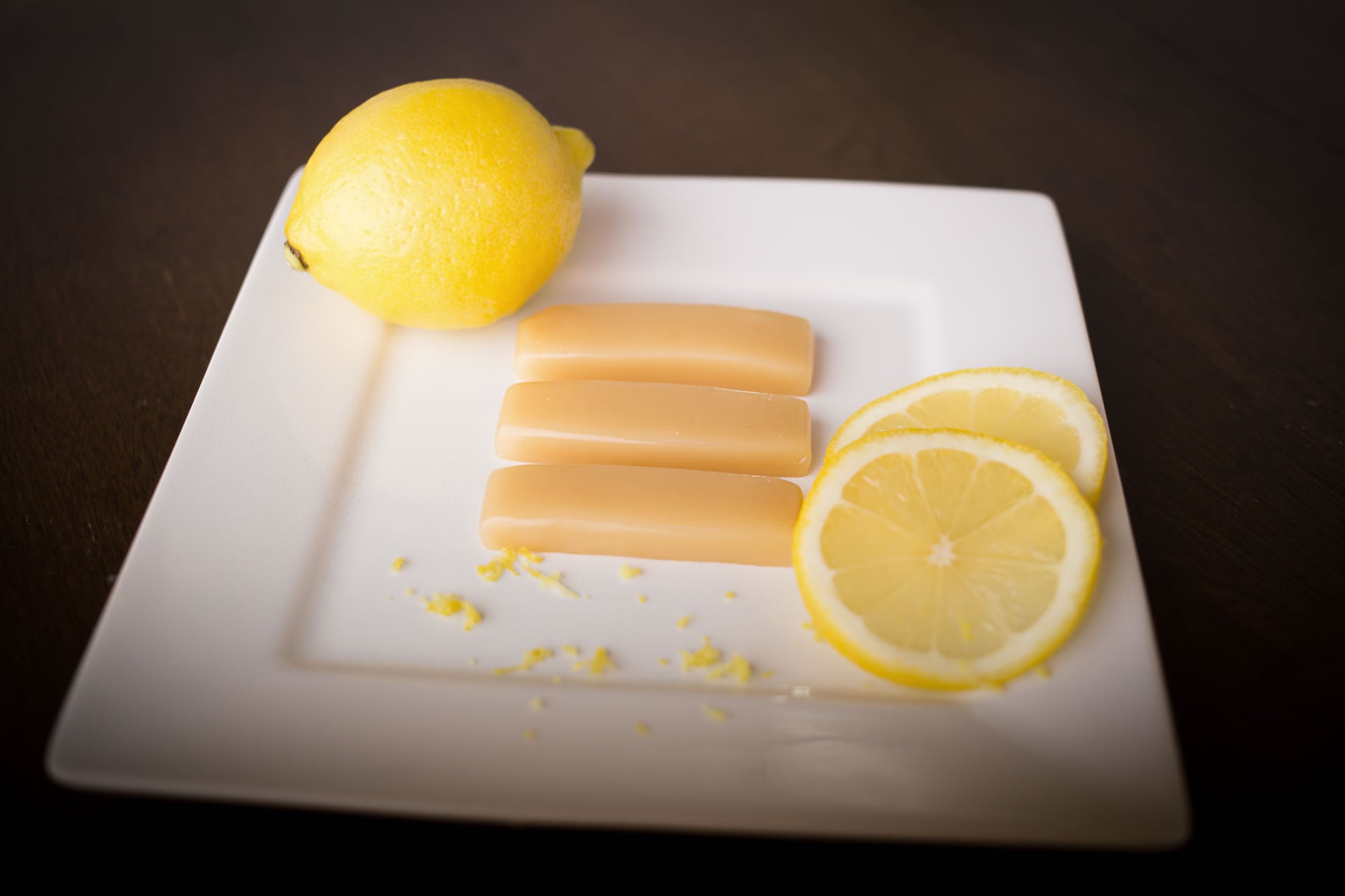 Lemon caramels on a white plate beside a lemon